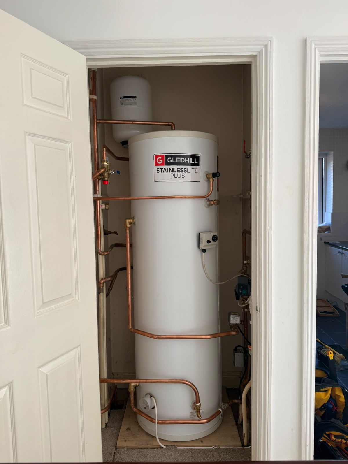 Gledhill StainlessLite Plus unvented hot water cylinder with expansion vessel and copper pipework installed in an airing cupboard in Bedfordshire