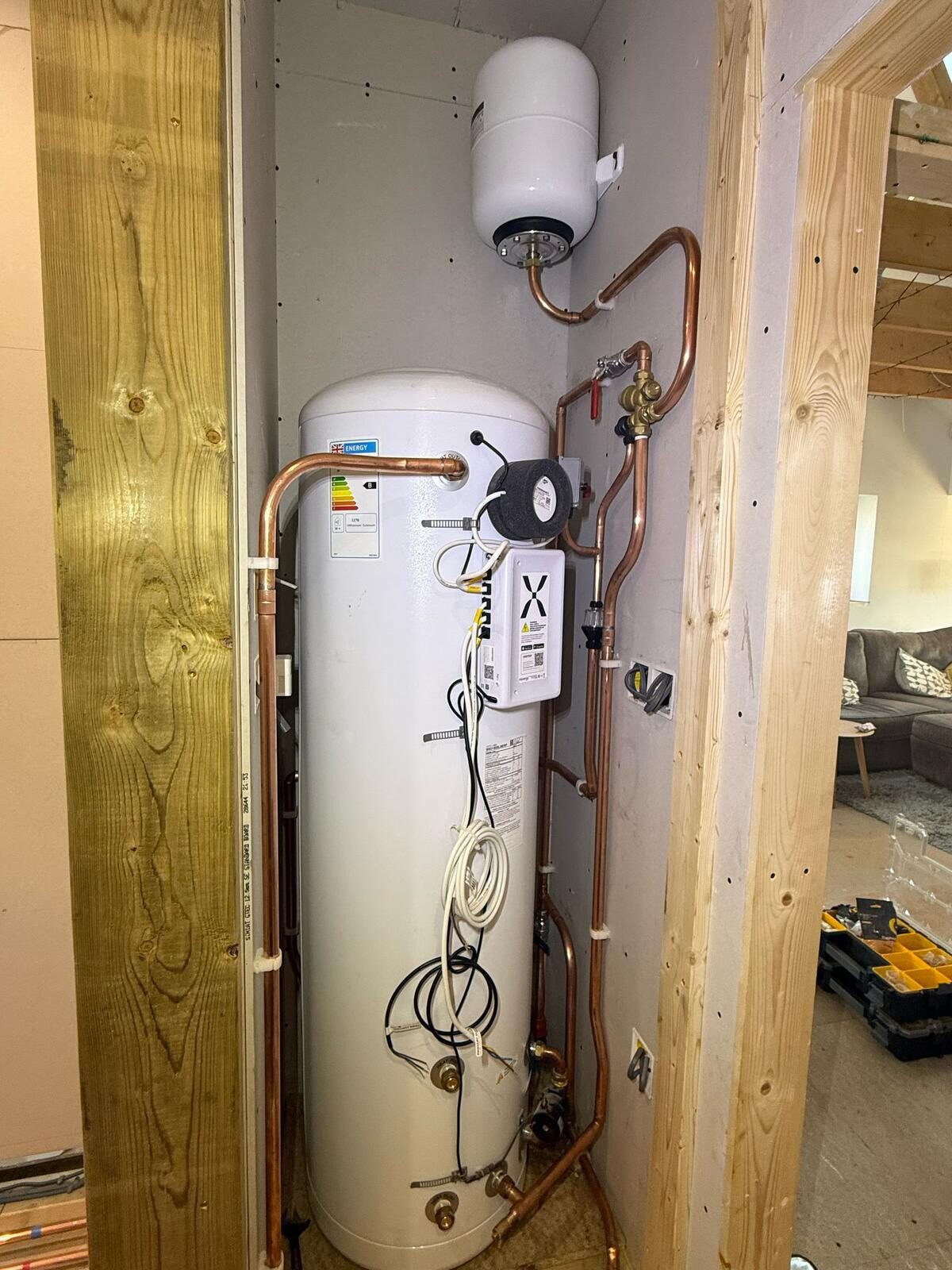 Mains-pressure unvented cylinder installation with expansion vessel, copper pipework and energy label in a Bedfordshire airing cupboard