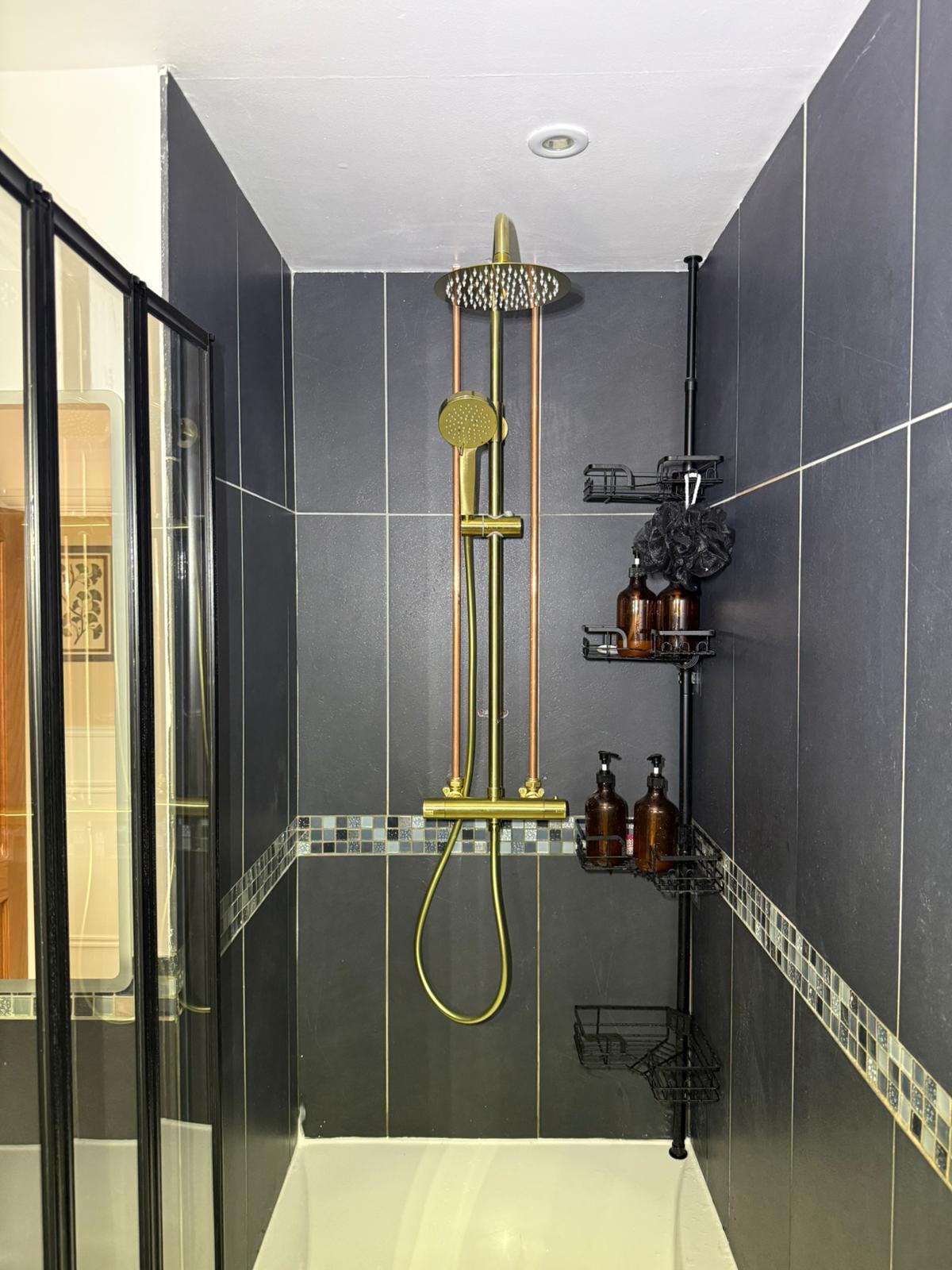 Modern walk-in shower with brushed brass rainfall shower set, dark grey large-format tiles and mosaic feature band — bathroom installation by On-Tap Plumbing & Heating